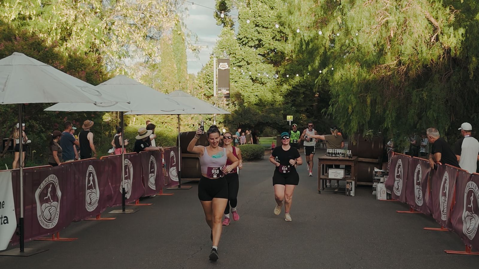 Runners crossing the finish chute past white umbrellas